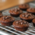 A beautifully frosted chocolate chip cupcake with a swirl of buttercream and a sprinkle of chocolate chips.